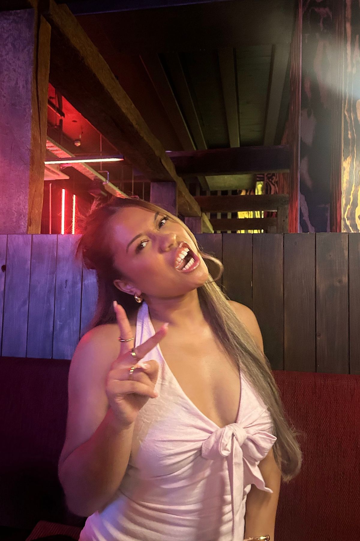 Angels in a white halter top, pointing playfully at the camera